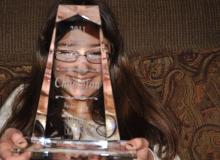 Elizabeth Nisly smiles behind her spelling bee trophy