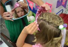 Regan checks her princess crown as Vanessa Wilson holds the mirror