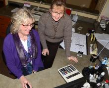 Carol Bradley (seated) instructs her replacement, Valerie Rogers